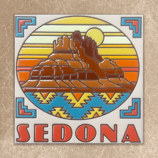 A square decorative tile or coaster featuring a colorful Sedona landscape design with layered rock formations, a yellow sun, and a blue patterned band, with the word SEDONA in large red letters at the bottom, shown on a textured beige background.