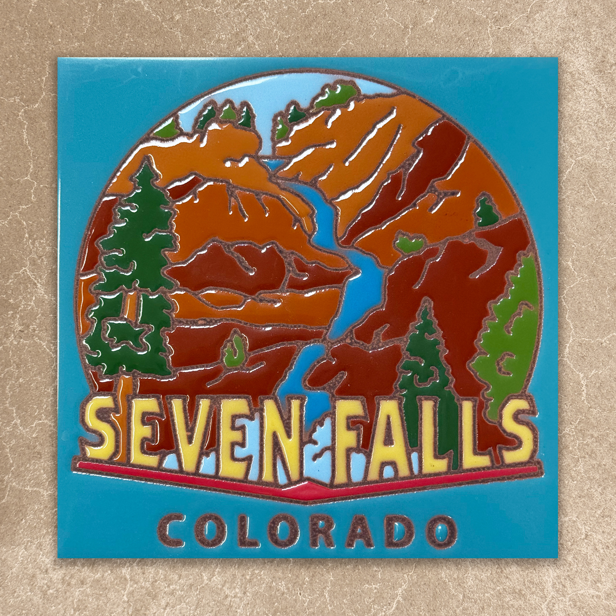 tile  with 'Seven Falls Colorado' design on a textured beige background