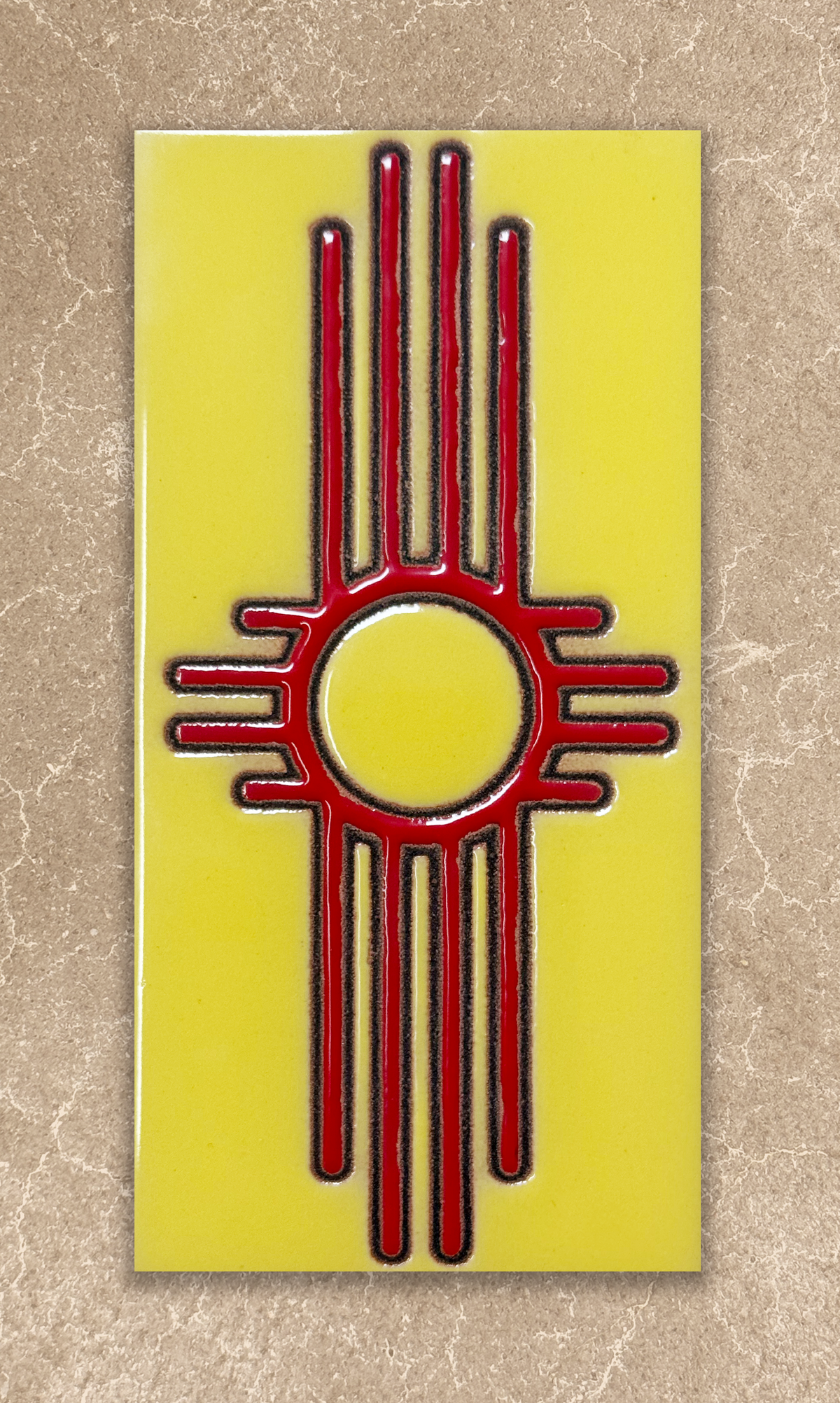 Red and black zia symbol on a yellow background ceramic tile