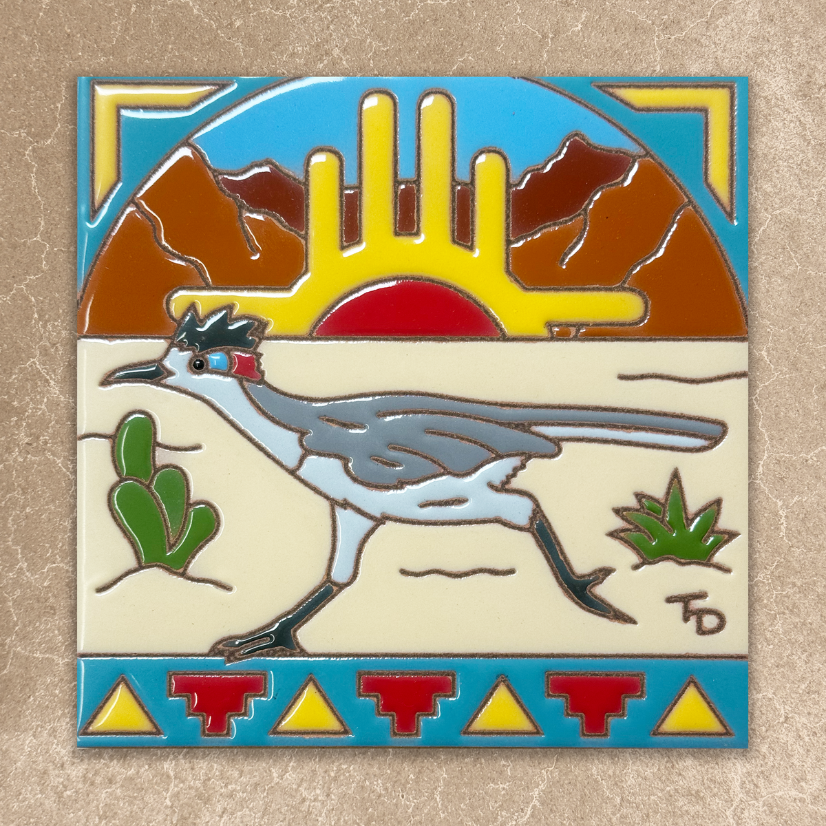 Decorative tile with a roadrunner, cacti, and desert landscape design on a beige background.