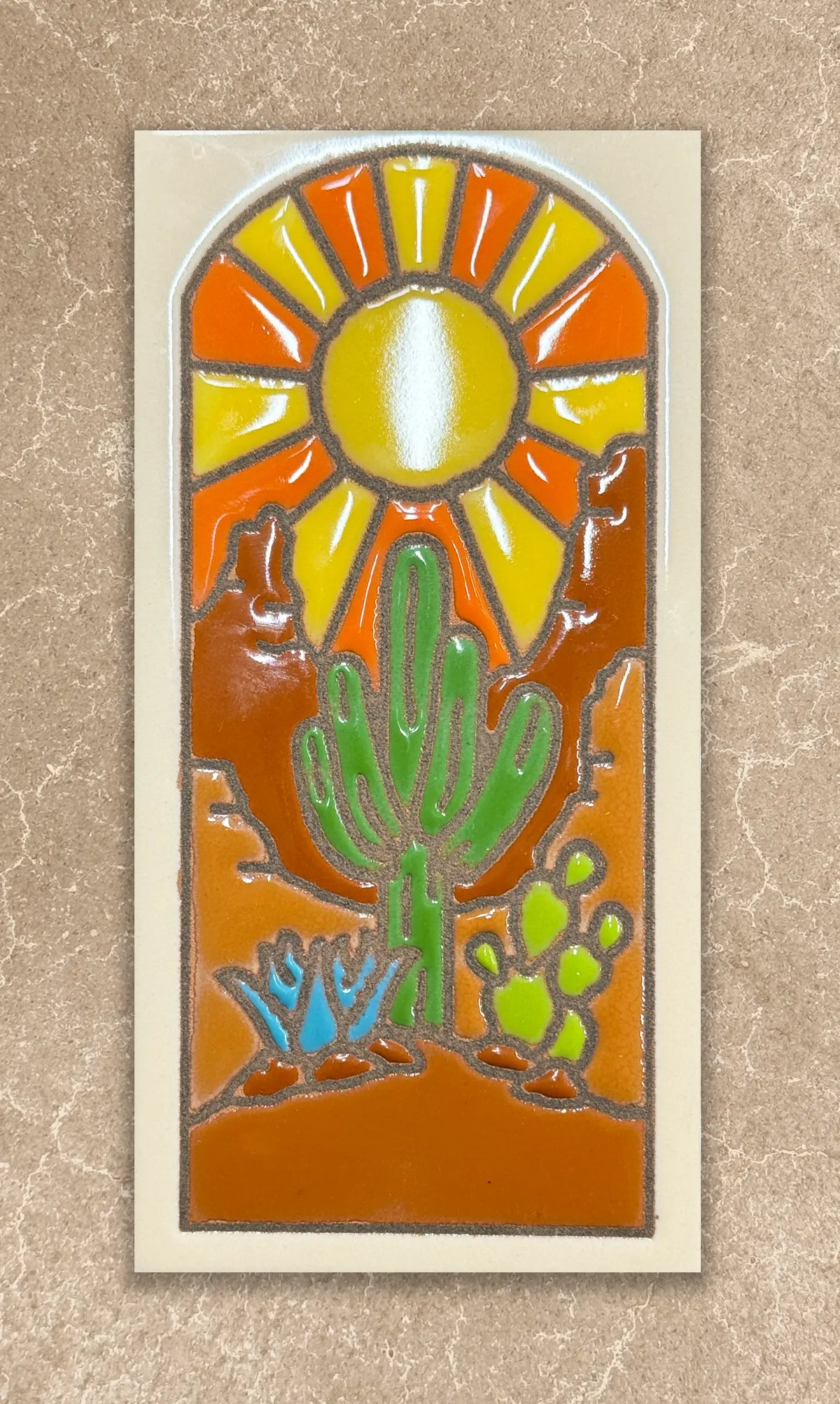 Decorative tile with a cactus and sun design on a beige background