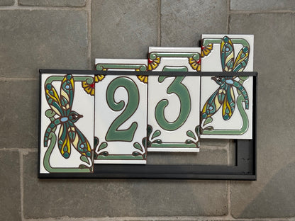 Set of decorative house number tiles with floral designs on a stone wall.