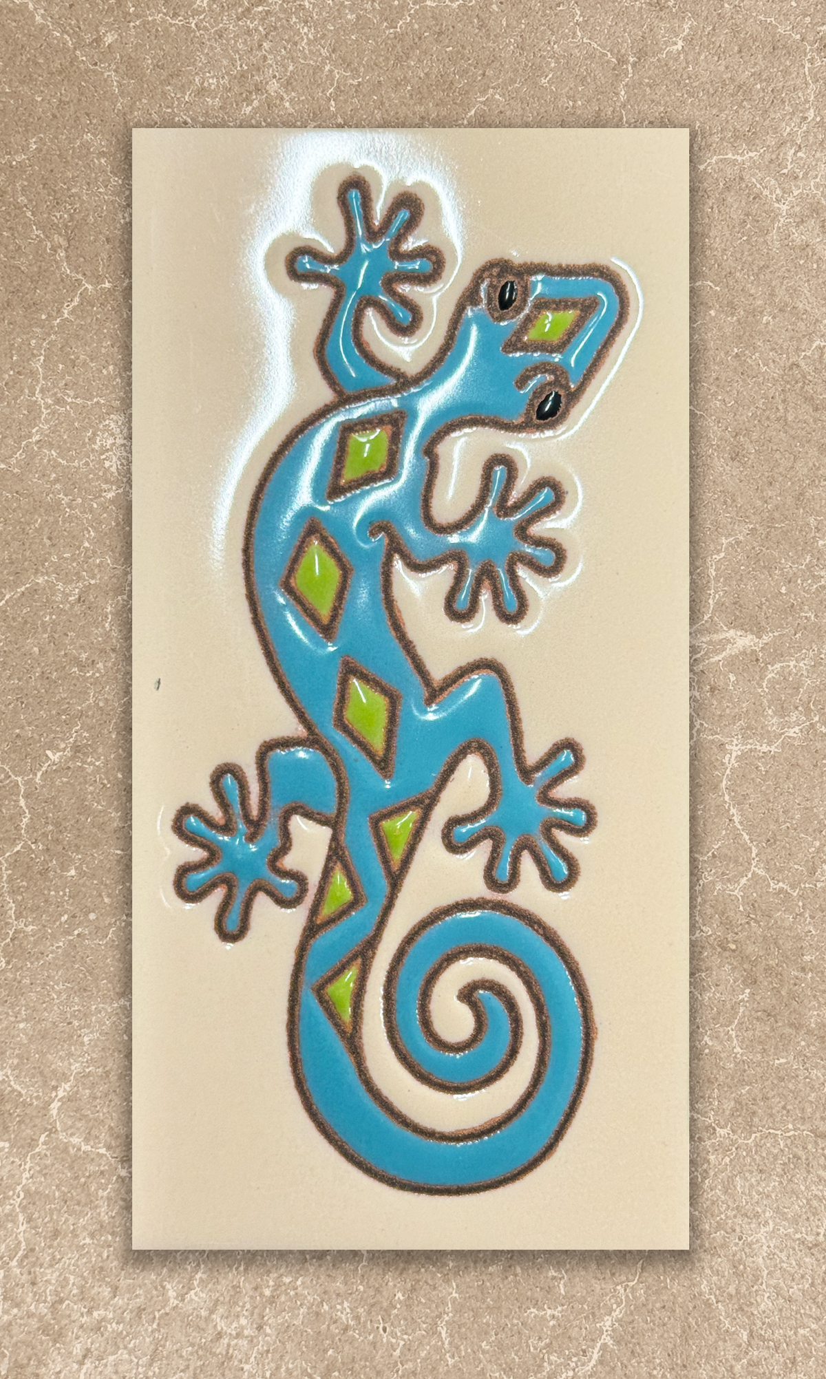 Decorative tile with a blue and green lizard design on a beige background