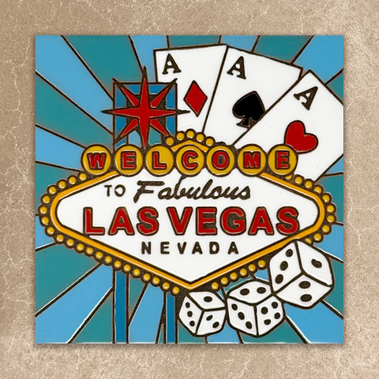 Decorative sign with 'Welcome to Fabulous Las Vegas Nevada' text, playing cards, and dice on a blue background.