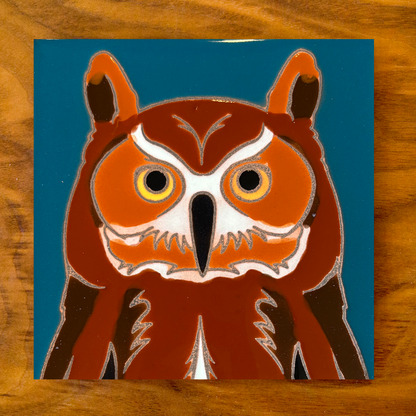 owl ceramic tile coaster on a blue background with wood table