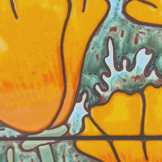 ceramic tile panel wall art with orange poppy flowers and mountains on a textured wall.