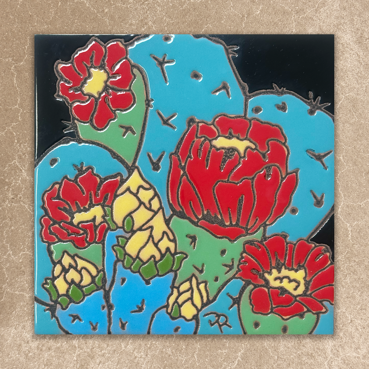 Decorative tile with red and yellow floral cactus design on a black background