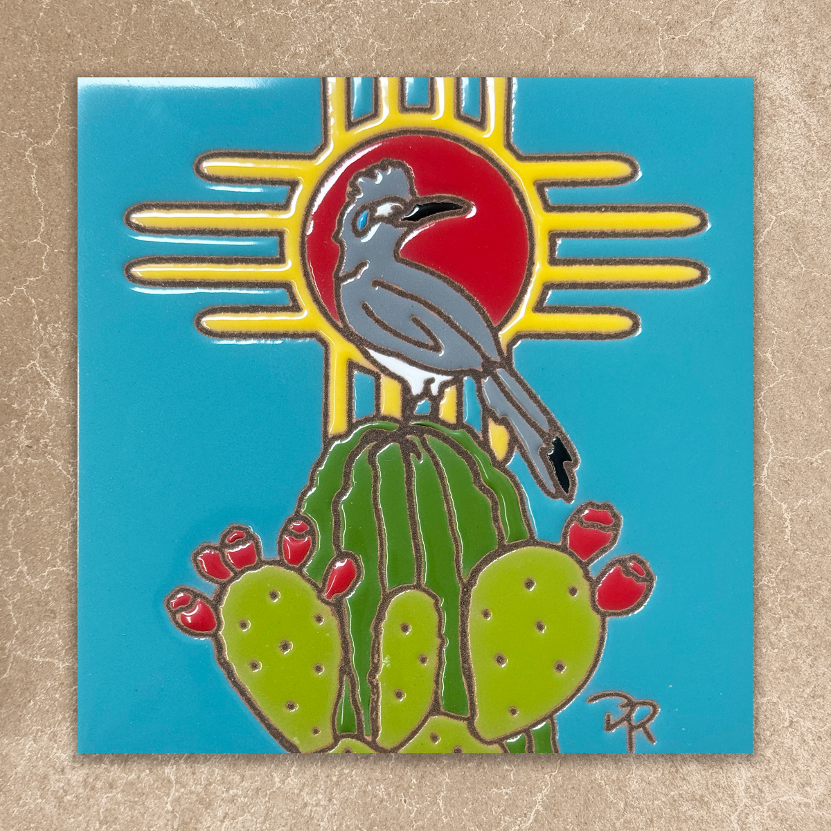 ceramic tile with a bird on a cactus and sun design on a blue background