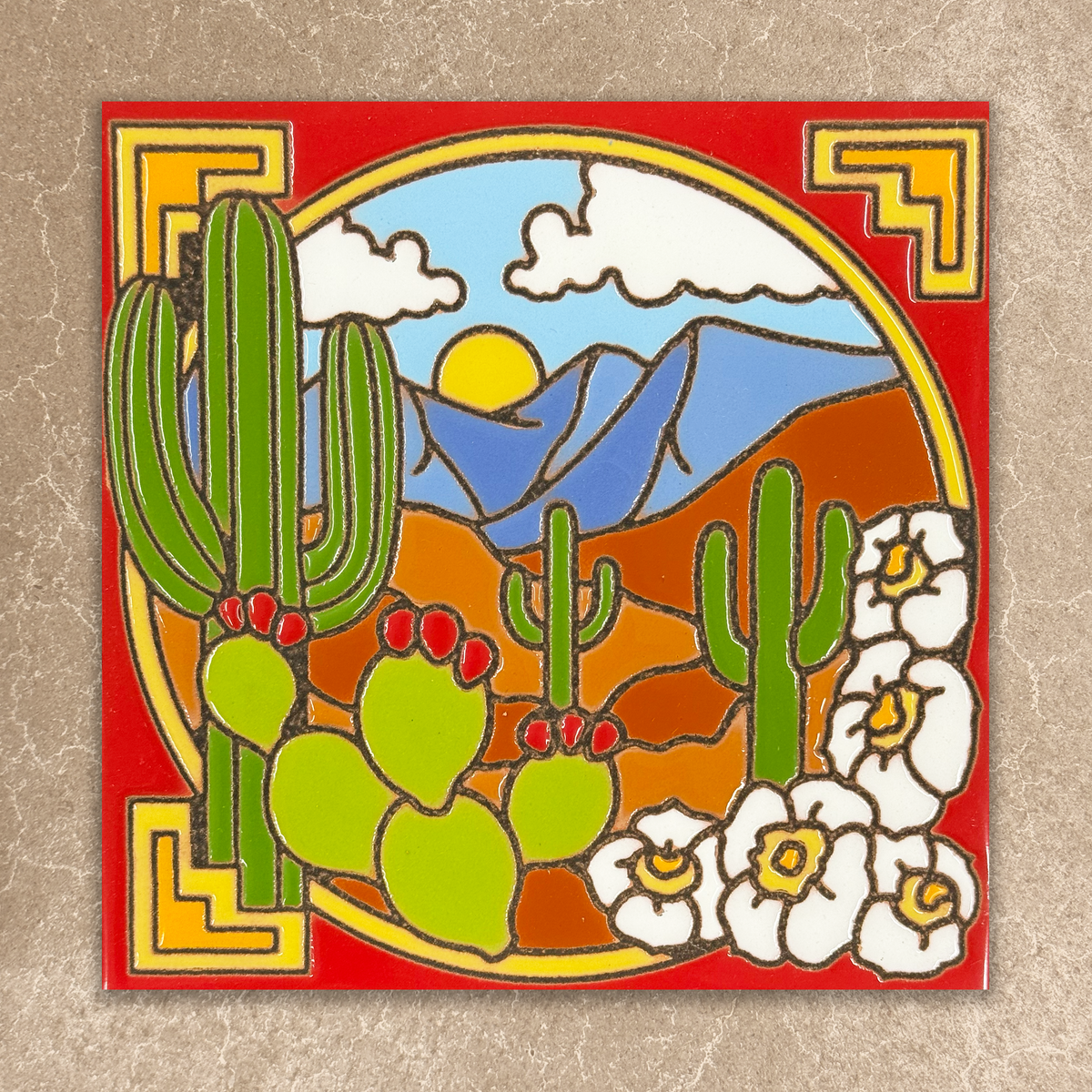 Decorative tile with desert scene featuring cacti, flowers, and mountains on a red background.