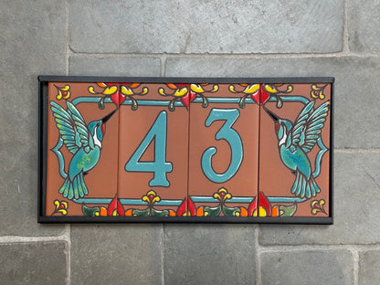 Decorative house number sign with '43' and hummingbirds on a stone wall background